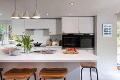 a kitchen with a counter with two chairs and a table at Beach Cottage and The Lobster Pot in St. Agnes