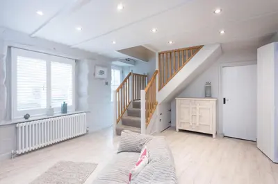 a living room with a staircase and a couch at Beach Cottage and The Lobster Pot in St. Agnes