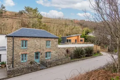 a stone house with a blue door on a street at Beach Cottage and The Lobster Pot in St. Agnes