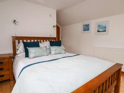 a bedroom with a large white bed with blue pillows at Little Orchard Barn in St Austell