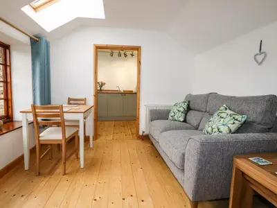 a living room with a couch and a table at Little Orchard Barn in St Austell
