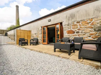 a patio with chairs and tables and a building at Wheal ProsperThe West Dry in St Austell