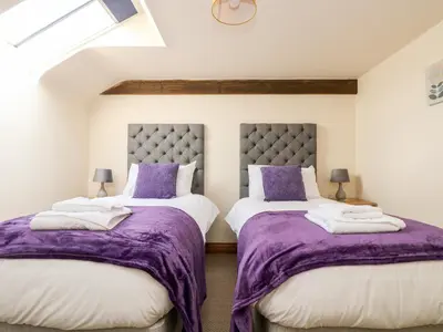 two beds in a room with purple blankets and pillows at Wheal ProsperThe West Dry in St Austell