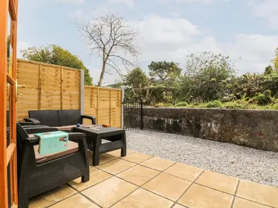a patio with chairs and a table and a fence at Wheal ProsperThe West Dry in St Austell