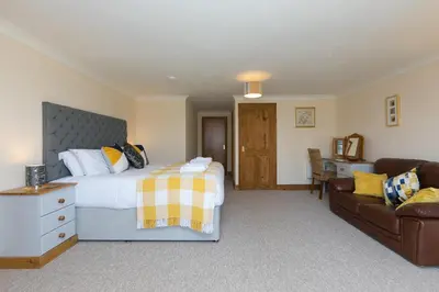a bedroom with a large bed and a couch at The KilnsThe West Dry in St Austell