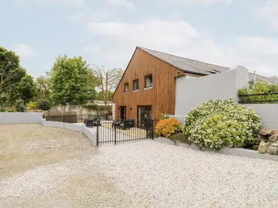 a barn house with a fence and flowers at The KilnsThe West Dry in St Austell