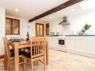 a kitchen with a wooden table and chairs and a stove at The LinneyThe West Dry in St Austell