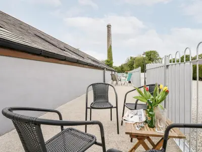 a patio with chairs and a table with flowers in a vase at The LinneyThe West Dry in St Austell