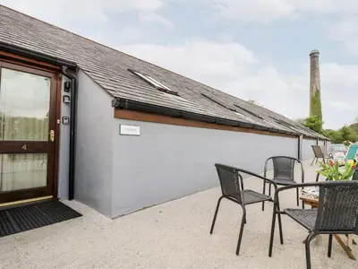 a patio with chairs and a table in front of a building at The LinneyThe West Dry in St Austell