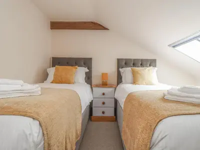 two twin beds in a room with a window at Water WheelsThe West Dry in St Austell