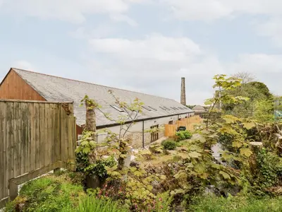 an old barn with a fence next to it at Water WheelsThe West Dry in St Austell
