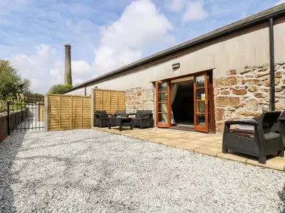 a stone building with a patio with chairs on it at RiversideThe West Dry in St Austell