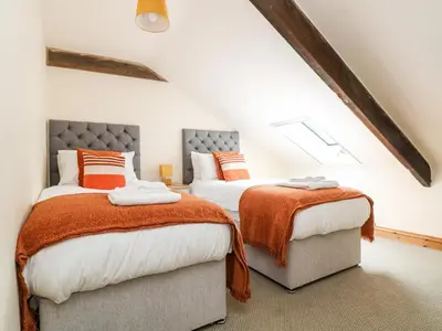 two beds in a attic bedroom with orange and white at RiversideThe West Dry in St Austell