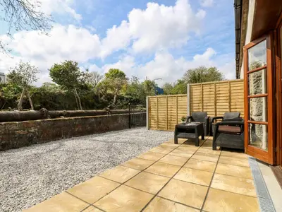 a patio with chairs and a table and a fence at RiversideThe West Dry in St Austell