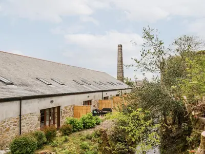 an old stone building with a chimney in the background at RiversideThe West Dry in St Austell