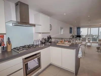 a kitchen with white cabinets and a stove top oven at Sky in St Ives