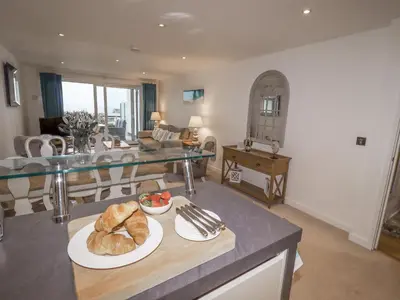 a kitchen and living room with a table with plates of bread at Sky in St Ives
