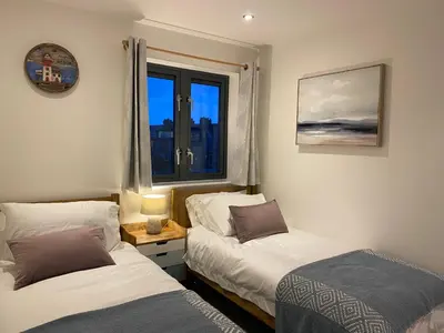 a bedroom with two beds and a window at Amazing 2-bedroom apartment with lovely sea views in Newquay