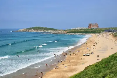 a group of people on a beach near the ocean at Amazing 2-bedroom apartment with lovely sea views in Newquay
