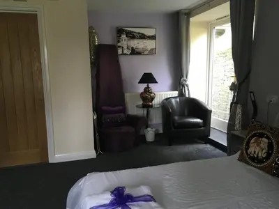 a bedroom with a bed and a chair and a window at Cherrywood Lodge in Looe