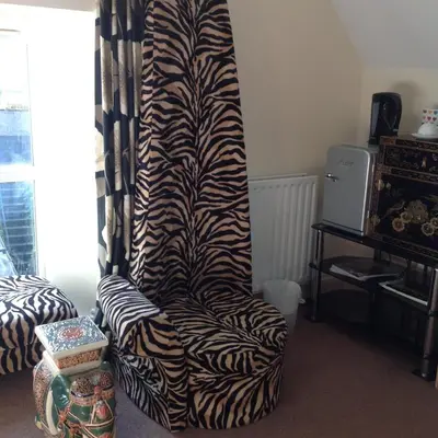 a zebra print chair in a living room with a curtain at Cherrywood Lodge in Looe