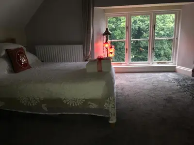 a bedroom with a bed and a large window at Cherrywood Lodge in Looe