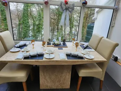 a dining room table with chairs and a large window at Cherrywood Lodge in Looe
