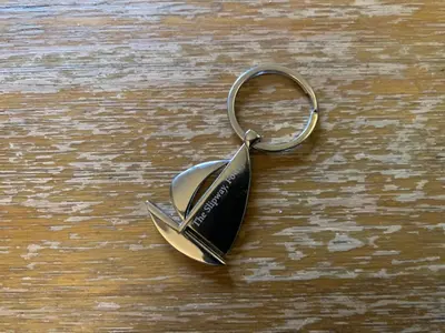 a small metal key chain on a wooden table at The Slipway Fowey Harbour Parking 1 Min & Garden in Fowey
