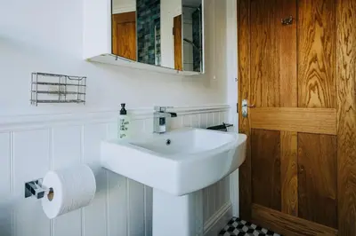 a bathroom with a white sink and a wooden door at The Slipway Fowey Harbour Parking 1 Min & Garden in Fowey