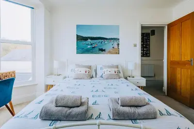 a bedroom with a bed and a view of a beach at The Slipway Fowey Harbour Parking 1 Min & Garden in Fowey