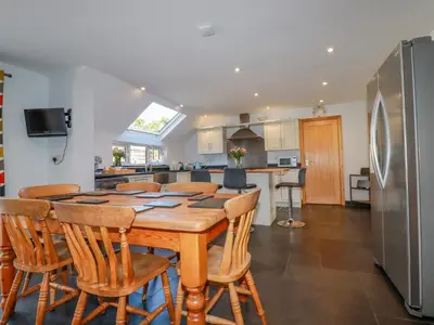 a kitchen with a wooden table and chairs and a refrigerator at Penlaurel in Bude