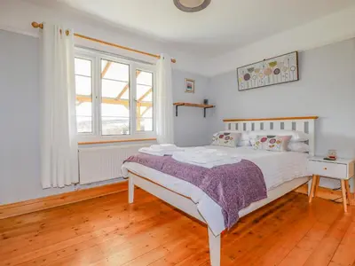 a white bedroom with a bed and a window at Penlaurel in Bude