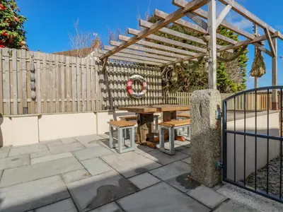 a wooden pergola with a wooden table in a patio at Penlaurel in Bude