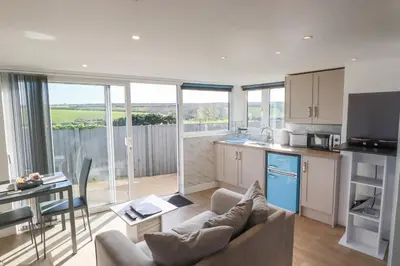 a kitchen and living room with a couch and a table at Gannel Hideaway in Newquay