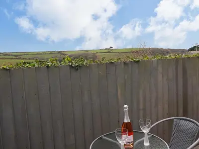 a bottle of wine sitting on a table with two glasses at Gannel Hideaway in Newquay