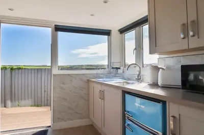 a kitchen with two large windows with a view of the ocean at Gannel Hideaway in Newquay