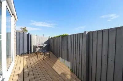 a wooden deck with a chair on a fence at Gannel Hideaway in Newquay