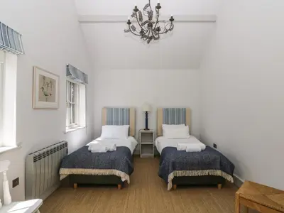 a bedroom with two beds and a chandelier at Wood Meadow in Helston