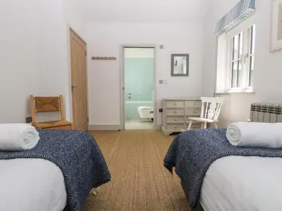 a bedroom with two beds and a bathroom at Wood Meadow in Helston