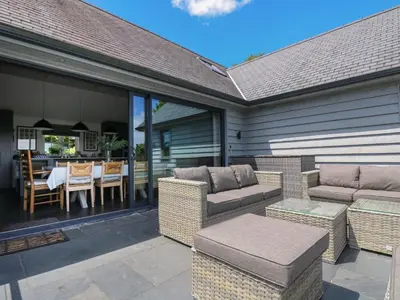 a patio with wicker furniture and a dining table at Wood Meadow in Helston
