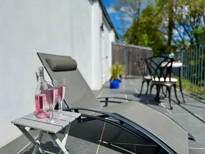 a table with two wine glasses on a patio at Trewethen Cottage Barn 2 near Port Isaac in Port Isaac