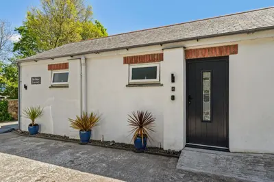 a white building with a black door and potted plants at Trewethen Cottage Barn 2 near Port Isaac in Port Isaac