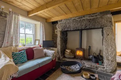 a living room with a stone fireplace and a couch at Kitts Cottage, Redruth, Cosy Cornish Retreat in Redruth