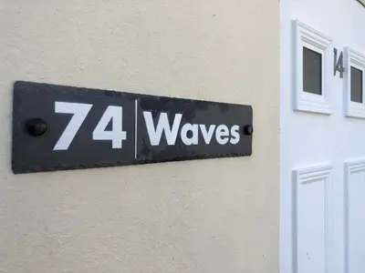 a sign on the side of a building that reads waves at Waves in Saint Columb Major