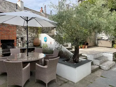 a patio with a table and chairs and an umbrella at Spring Garden Cottage in Wadebridge