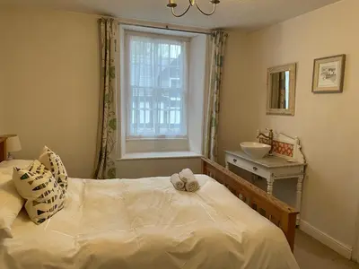a bedroom with a bed and a sink and a window at Spring Garden Cottage in Wadebridge