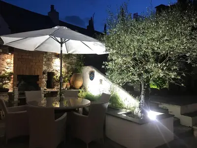 a table with an umbrella in a garden at night at Spring Garden Cottage in Wadebridge