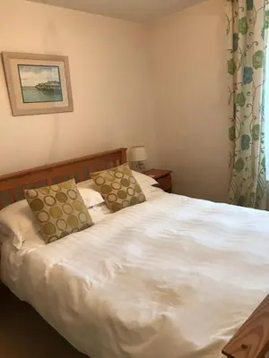 a bedroom with a white bed with two pillows at Spring Garden Cottage in Wadebridge