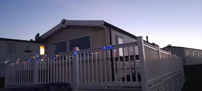 a house with a white fence with christmas lights at 58 Newquay View, Newquay Bay Resort in Porth