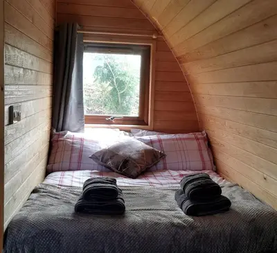 a bed in a small room with a window at Glamping Pods Nr Port Isaac in Port Isaac